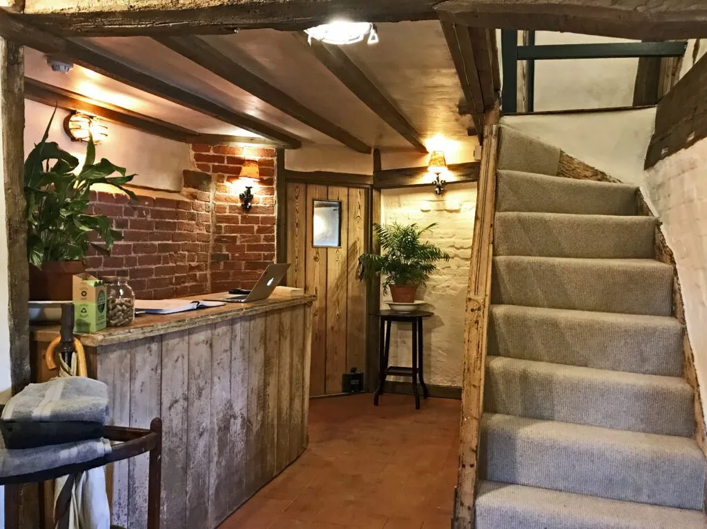 Strand House reception: oak-beamed hall with a timber desk and a carpeted staircase