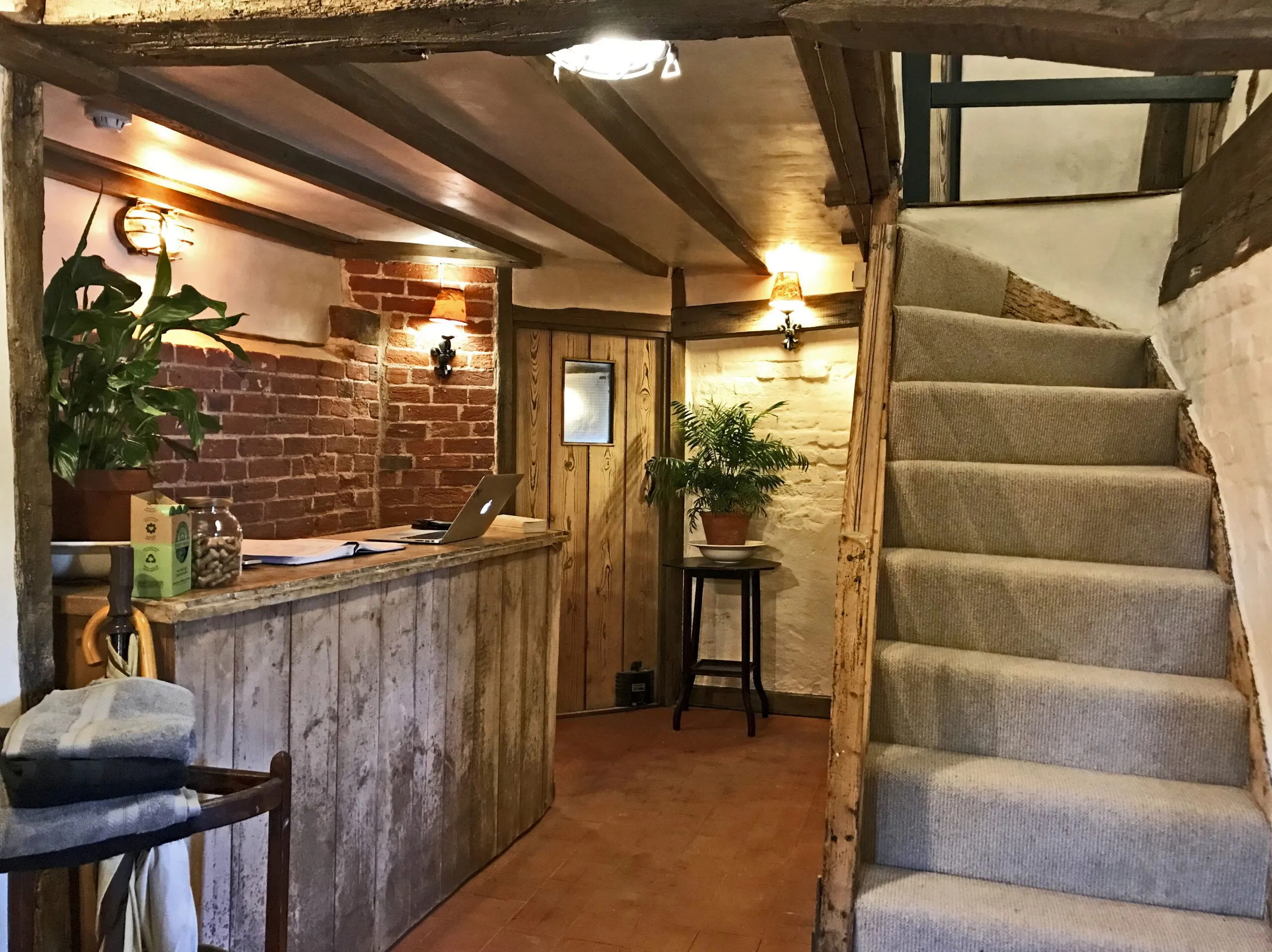 Strand House reception: oak-beamed hall with a timber desk and a carpeted staircase