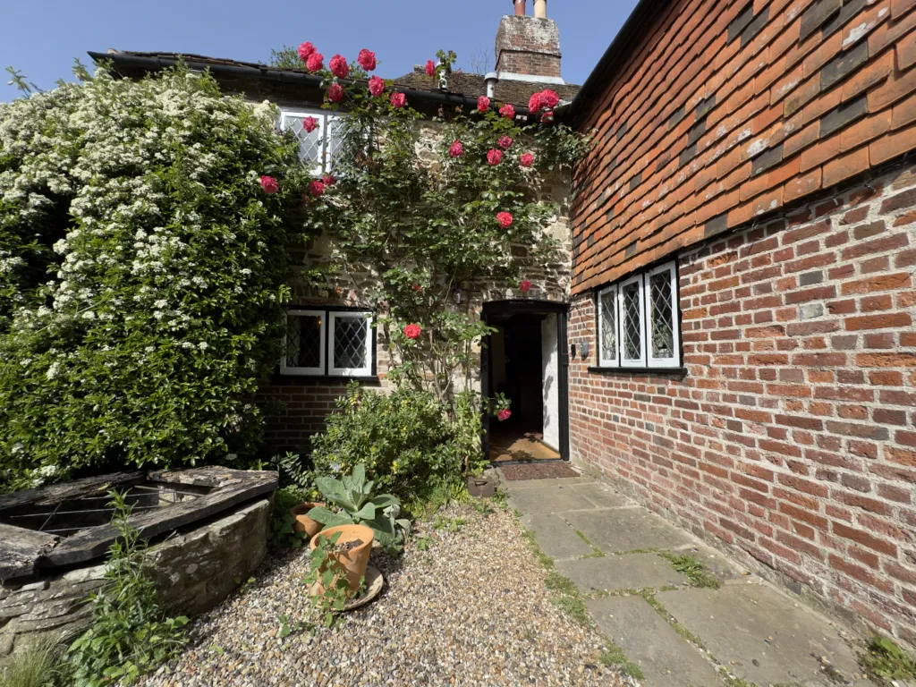 A rose-covered brick courtyard and open doorway at Strand House