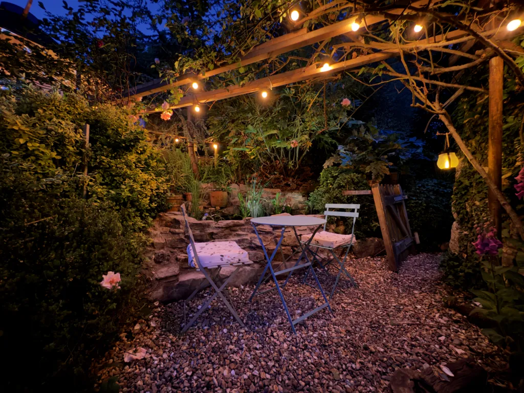 Garden seating under a pergola hung with lights at night