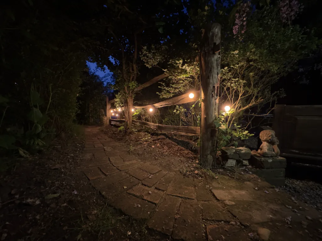 A stone path lit by lanterns and festoon lights at night