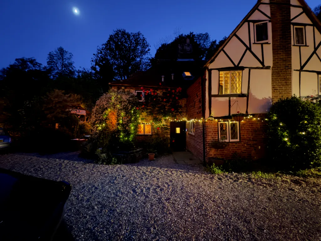 Strand House at night, with lit windows and lights strung along the wall